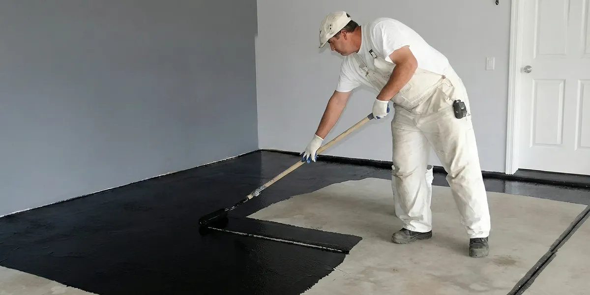 basement waterproofing professional applying waterproof coating to protect a basement floor in Memphis, TN