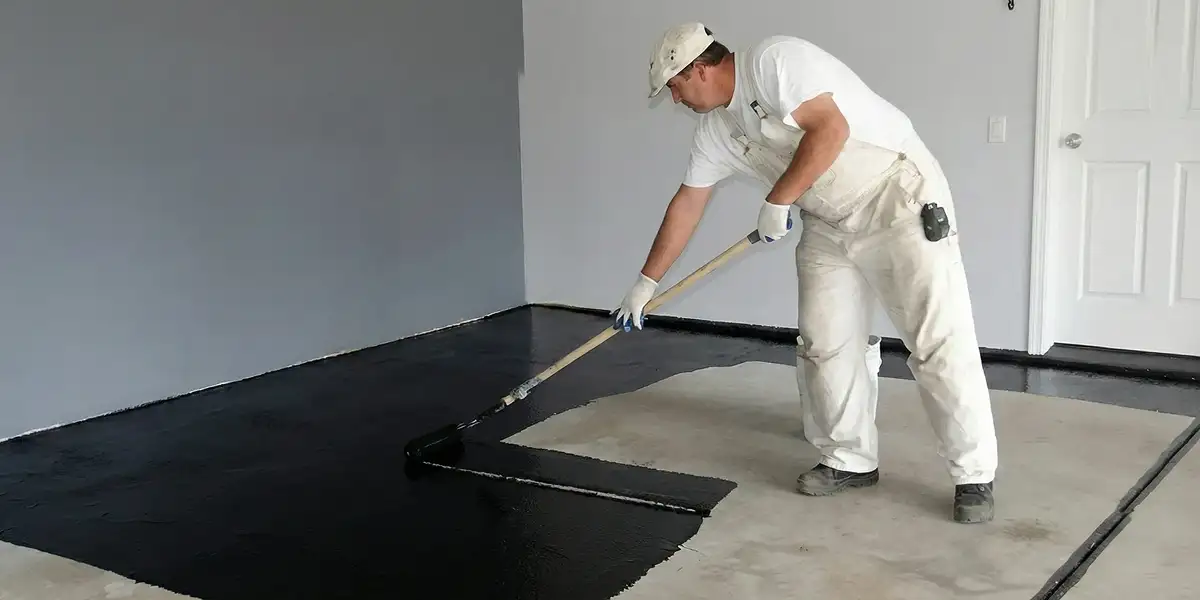 basement waterproofing professional applying waterproof coating to protect a basement floor in Memphis, TN